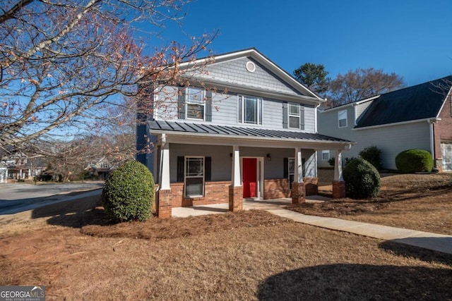 view of front of property with brick siding, a porch, metal roof, and a standing seam roof