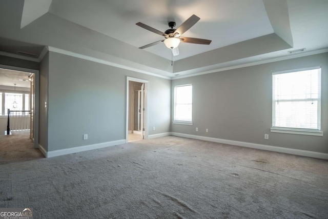 empty room with a tray ceiling, visible vents, baseboards, and carpet floors