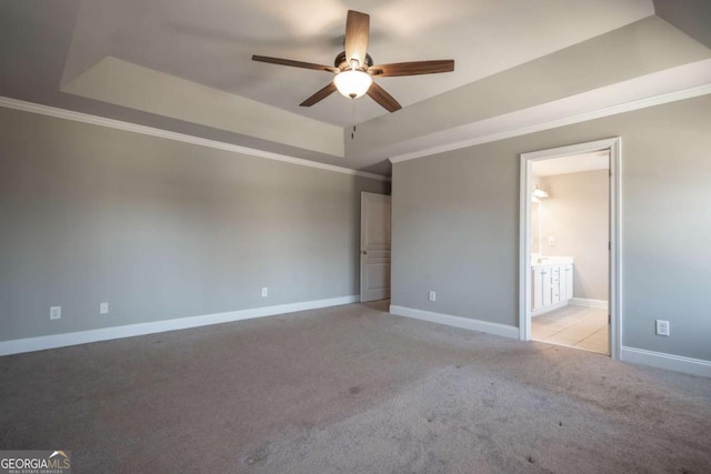 unfurnished bedroom featuring a raised ceiling, ornamental molding, baseboards, and light carpet