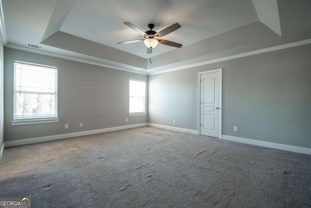 empty room featuring visible vents, carpet flooring, a raised ceiling, and baseboards