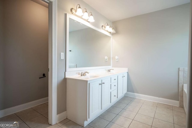 bathroom with a sink, baseboards, double vanity, and tile patterned flooring