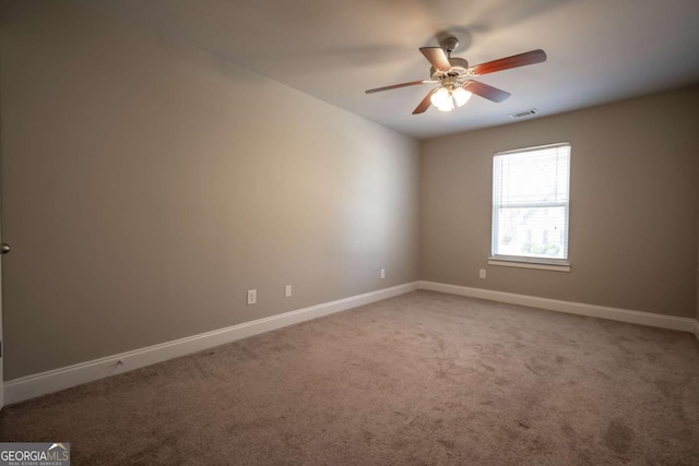 carpeted spare room featuring visible vents, baseboards, and ceiling fan