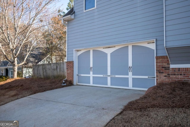 garage with concrete driveway and fence