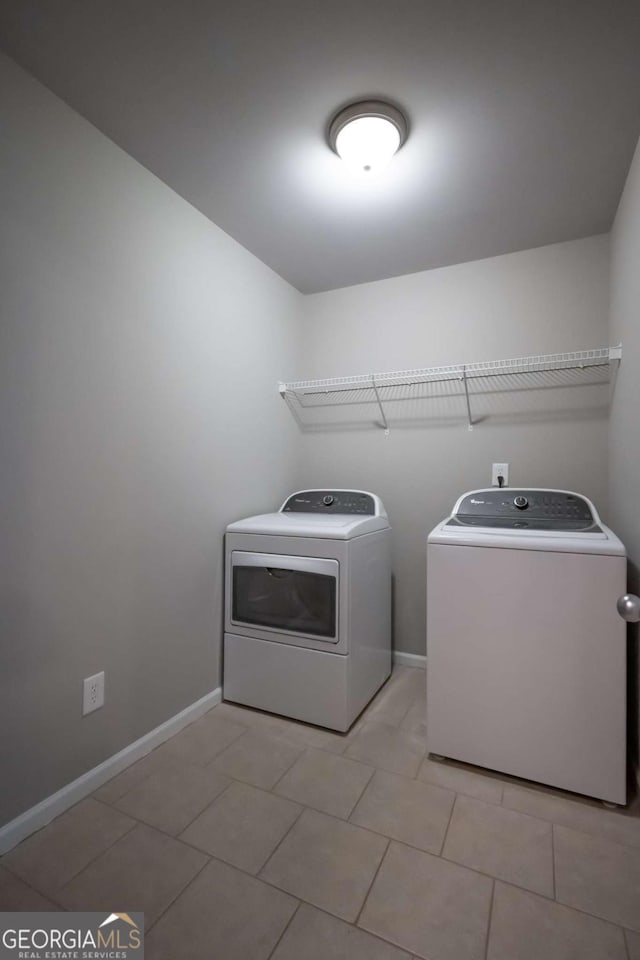 washroom featuring laundry area, light tile patterned flooring, separate washer and dryer, and baseboards