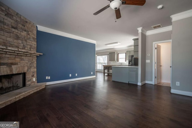 unfurnished living room with dark wood-style floors, a fireplace, crown molding, and baseboards