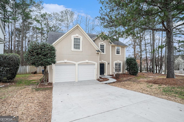 traditional-style home featuring stucco siding, driveway, an attached garage, and fence