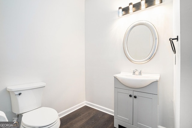 bathroom with toilet, vanity, baseboards, and wood finished floors