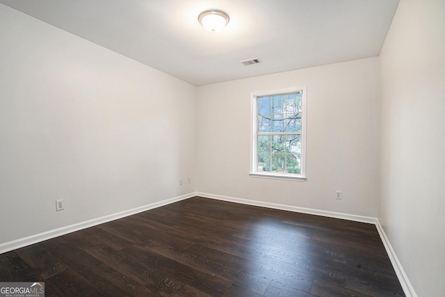 unfurnished room with visible vents, baseboards, and dark wood-style flooring