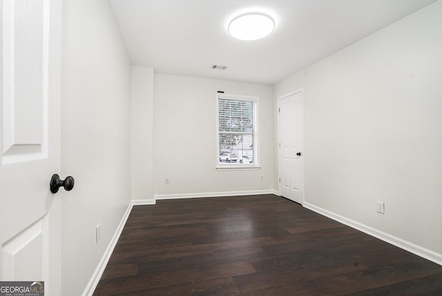 spare room featuring dark wood finished floors, baseboards, and visible vents