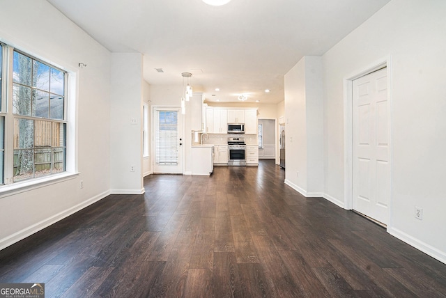 unfurnished living room featuring dark wood-type flooring, baseboards, and a sink