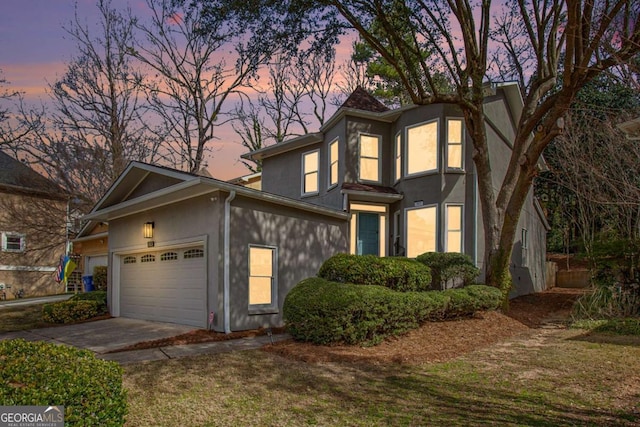 traditional-style home with stucco siding, driveway, and an attached garage