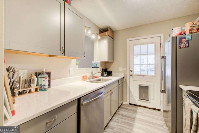 kitchen featuring a sink, stainless steel appliances, gray cabinetry, and light countertops