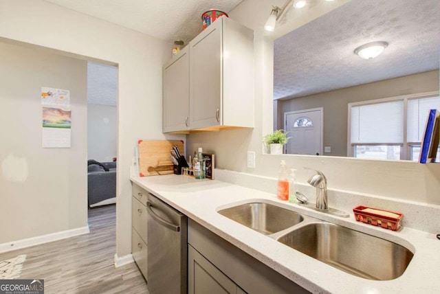 kitchen featuring a sink, light wood-style floors, a textured ceiling, and dishwasher