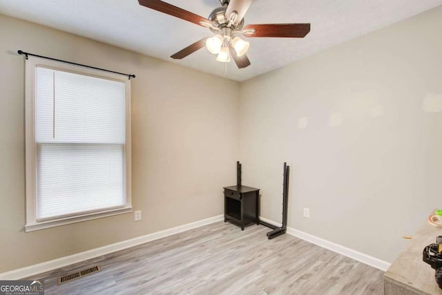 spare room featuring a ceiling fan, baseboards, visible vents, and light wood finished floors