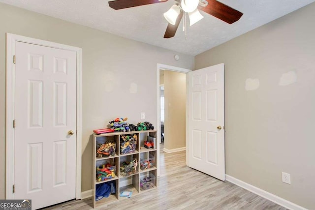 recreation room featuring baseboards, wood finished floors, and a ceiling fan