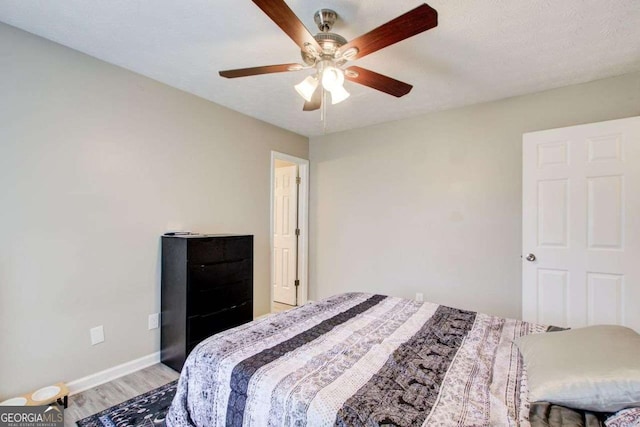 bedroom with light wood-style flooring, baseboards, and ceiling fan