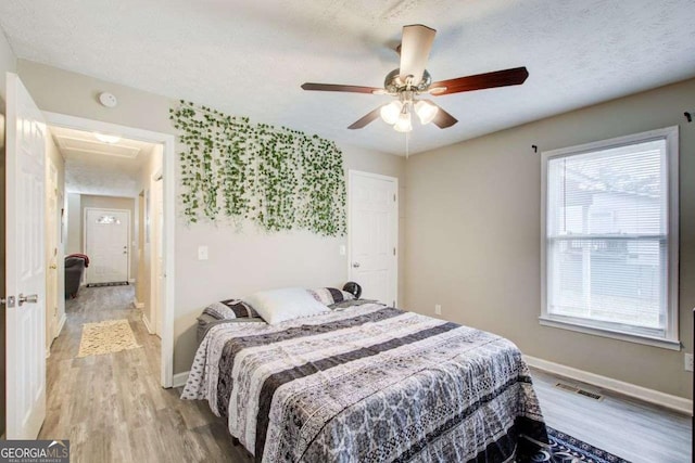 bedroom featuring a textured ceiling, light wood-type flooring, and baseboards