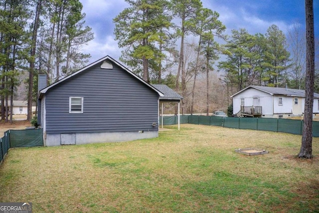 exterior space with a yard, a fenced backyard, and a chimney