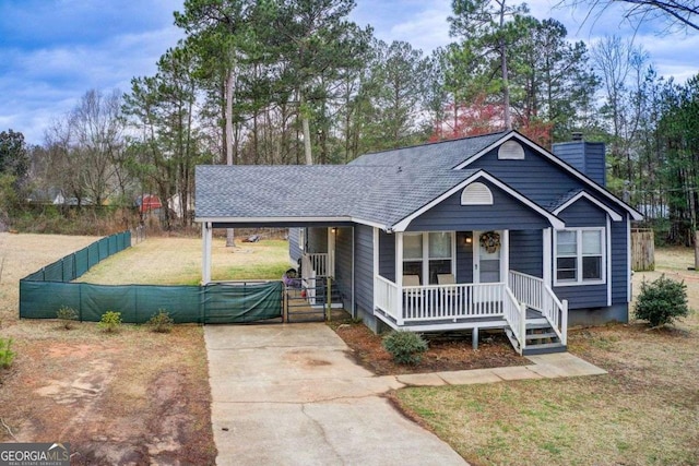 view of front of home featuring a porch, a chimney, concrete driveway, a carport, and a front lawn