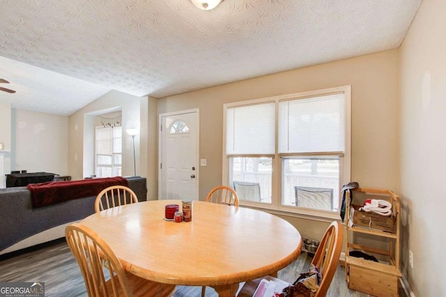 dining area with lofted ceiling, a textured ceiling, wood finished floors, and a ceiling fan