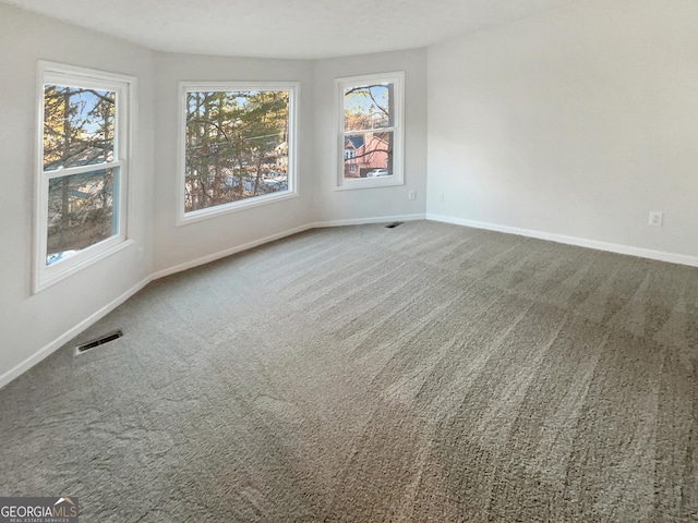 carpeted empty room featuring visible vents and baseboards