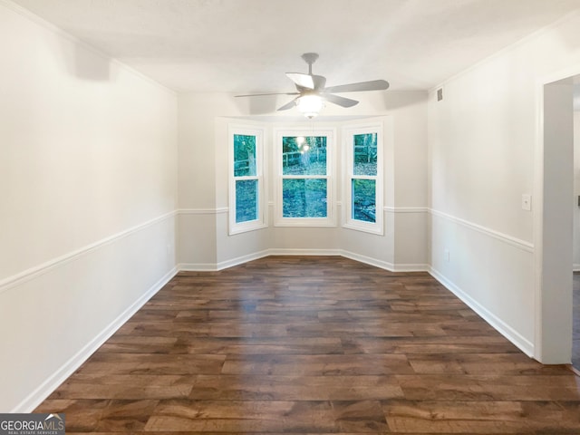 unfurnished room featuring baseboards, dark wood finished floors, a ceiling fan, and crown molding