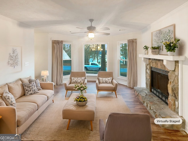 living area with a fireplace, plenty of natural light, wood finished floors, and a ceiling fan