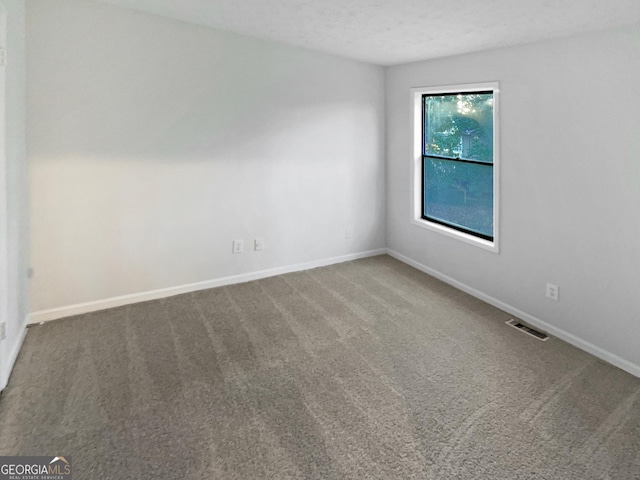 carpeted spare room with visible vents, baseboards, and a textured ceiling