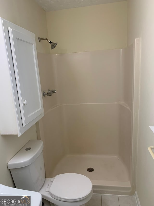 bathroom with tile patterned floors, toilet, and a walk in shower