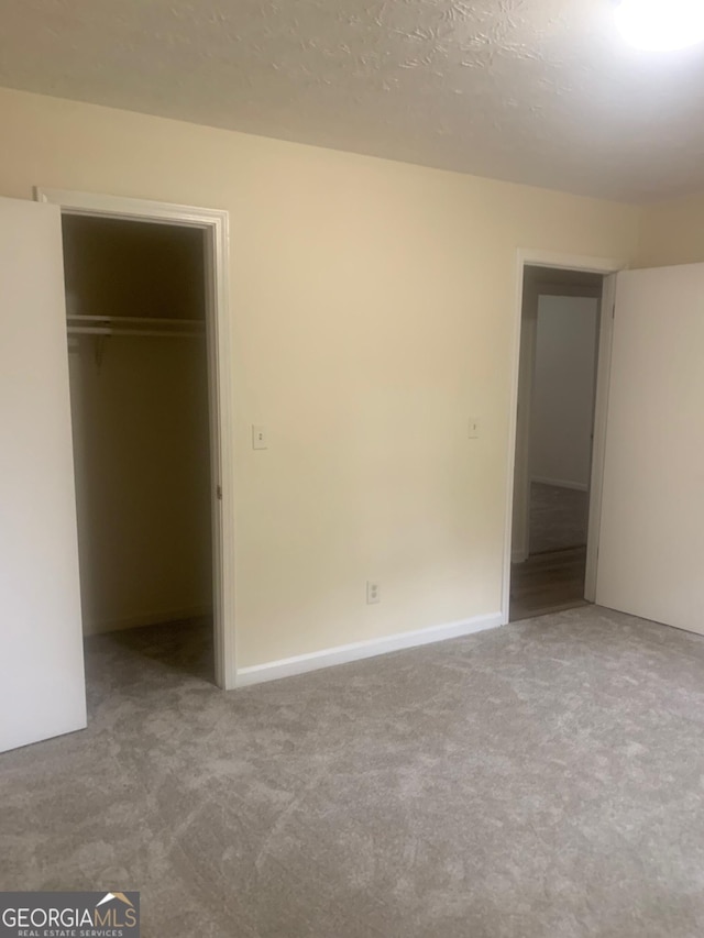 unfurnished bedroom featuring a closet, carpet, and a textured ceiling