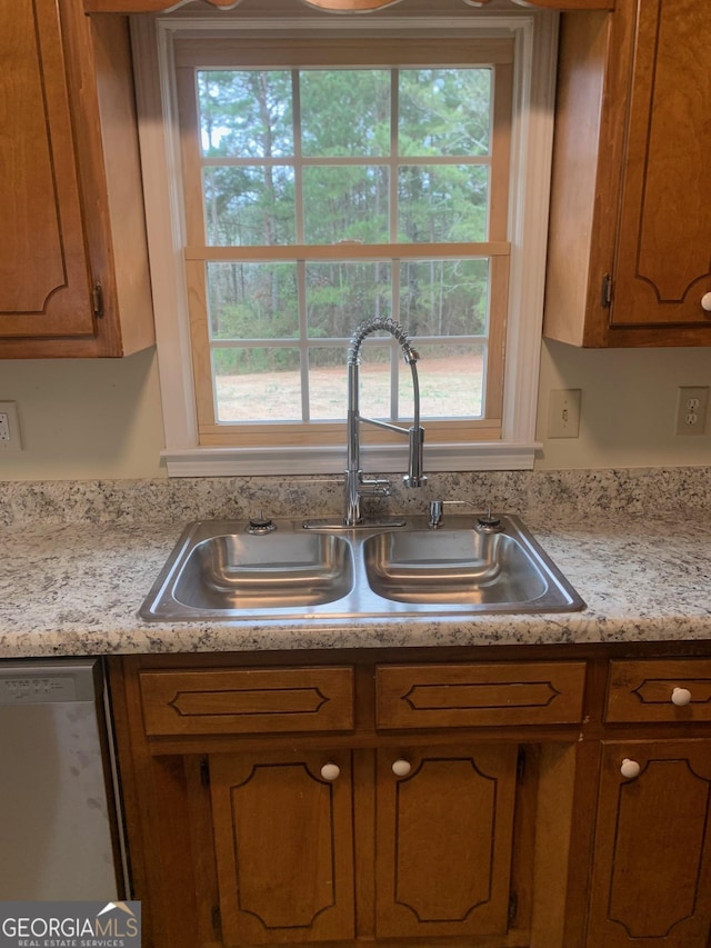 kitchen with dishwasher, brown cabinets, and a sink