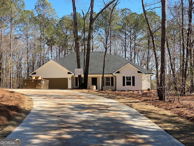 view of front of property with concrete driveway, a garage, and a shingled roof