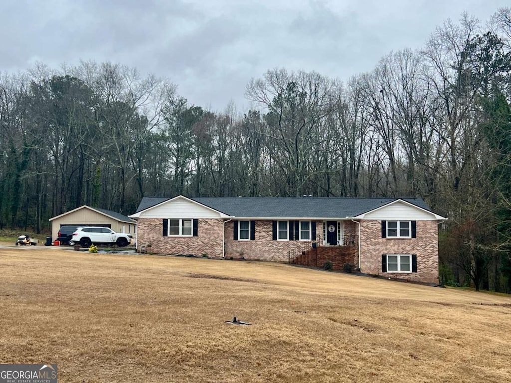 view of front facade with an outbuilding, brick siding, and a front lawn