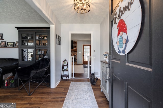 entrance foyer with visible vents, a notable chandelier, a textured ceiling, baseboards, and dark wood-style flooring