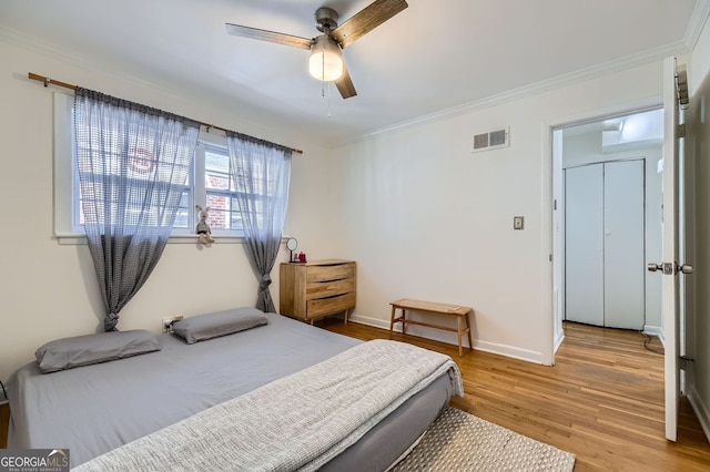 bedroom featuring light wood finished floors, visible vents, baseboards, ornamental molding, and a ceiling fan