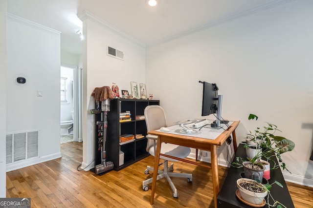 home office featuring visible vents, ornamental molding, and light wood-style flooring