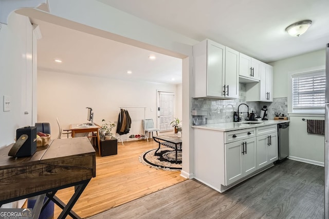 kitchen with dark wood-style flooring, a sink, decorative backsplash, light countertops, and dishwasher