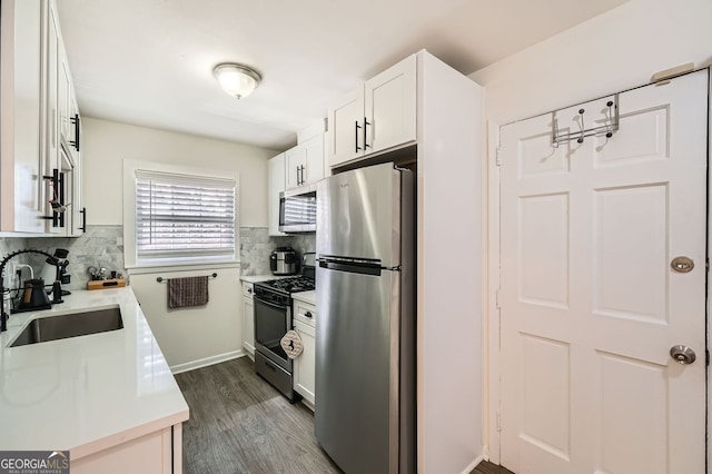 kitchen with backsplash, light countertops, white cabinets, stainless steel appliances, and a sink