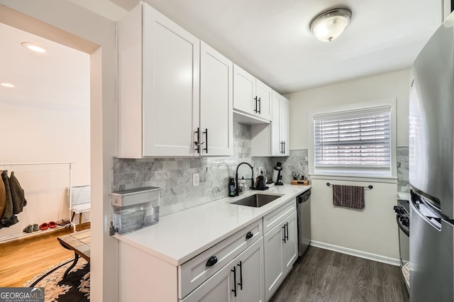 kitchen featuring a sink, dark wood-style floors, appliances with stainless steel finishes, light countertops, and decorative backsplash