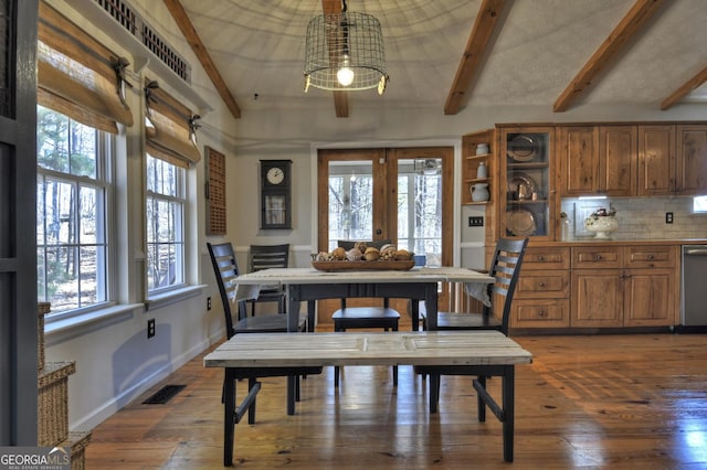 dining room with hardwood / wood-style floors, visible vents, baseboards, vaulted ceiling with beams, and french doors