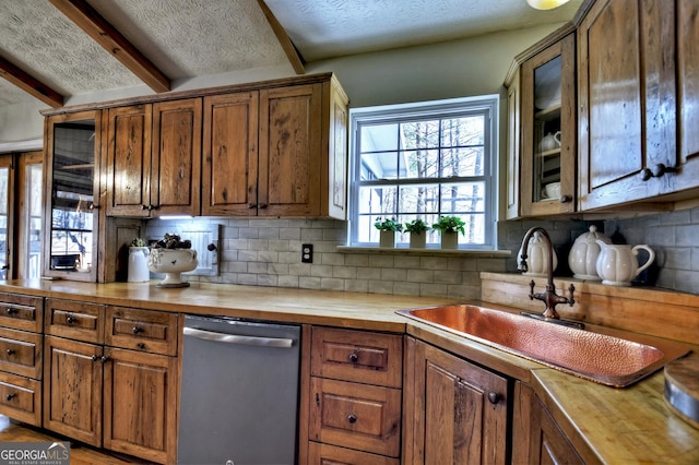 kitchen with butcher block countertops, backsplash, a sink, and stainless steel dishwasher