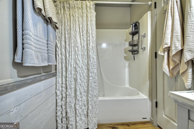 bathroom featuring shower / bath combination with curtain, wooden walls, and wood finished floors