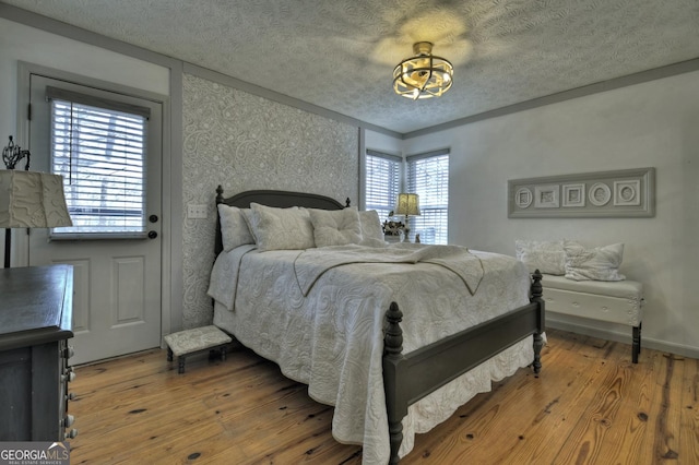 bedroom with a textured ceiling, baseboards, and hardwood / wood-style flooring