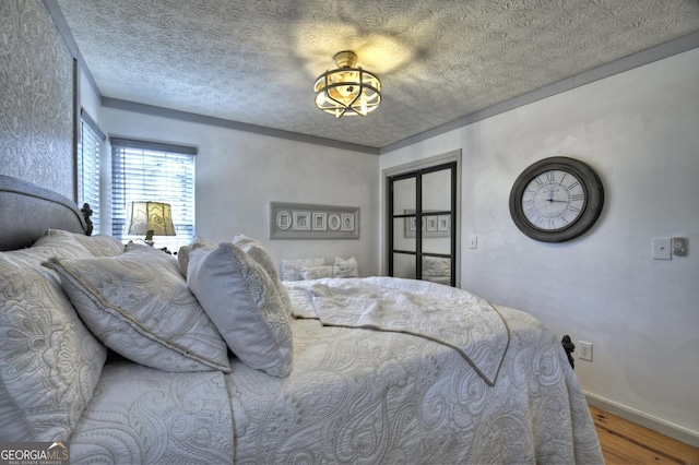 bedroom featuring a textured ceiling, baseboards, and wood finished floors