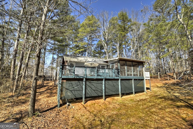 rear view of house featuring a wooden deck and a sunroom