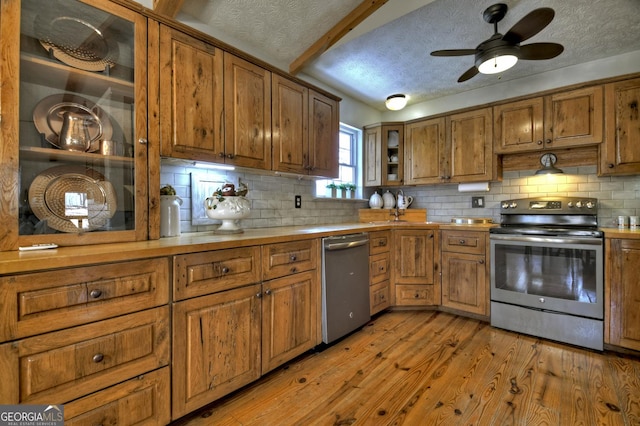 kitchen with a textured ceiling, brown cabinets, light wood finished floors, and stainless steel appliances