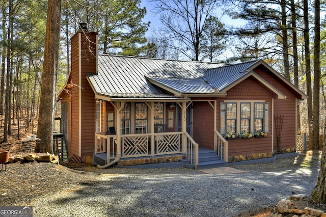 rustic home featuring metal roof, covered porch, a chimney, and a standing seam roof