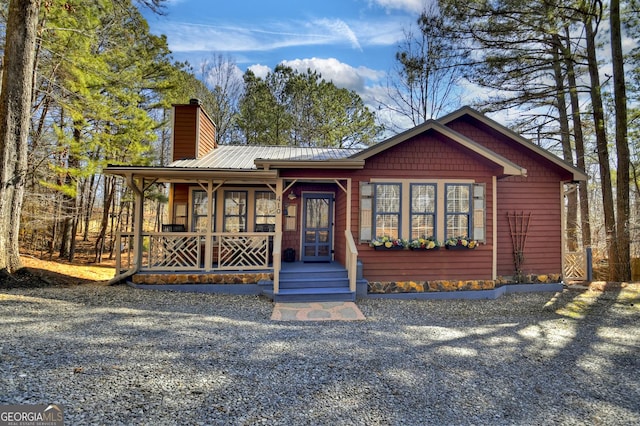 rustic home featuring metal roof, a porch, and a chimney