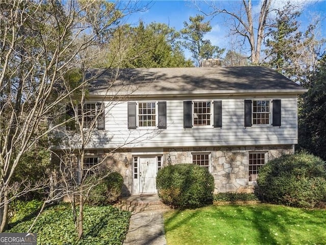 colonial inspired home with a front yard and stone siding