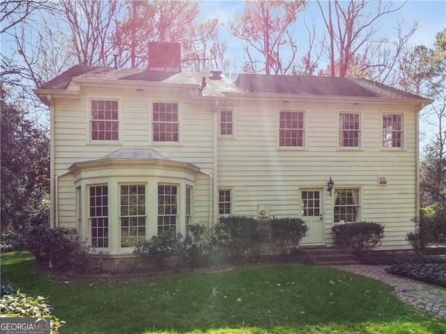 view of front of home featuring a front lawn, a chimney, and entry steps